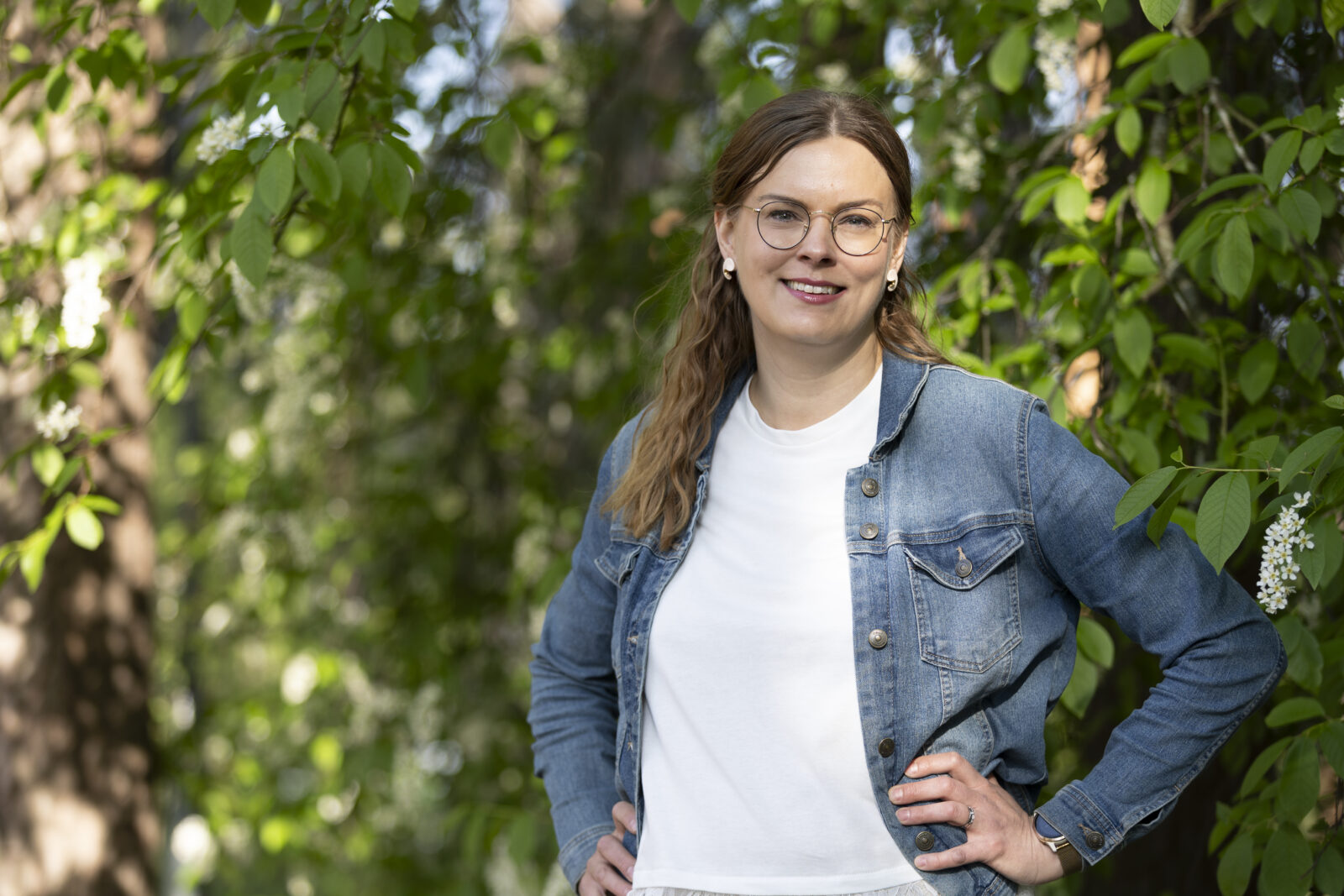 Sari Kokko seisoo kukkivan tuomen alla