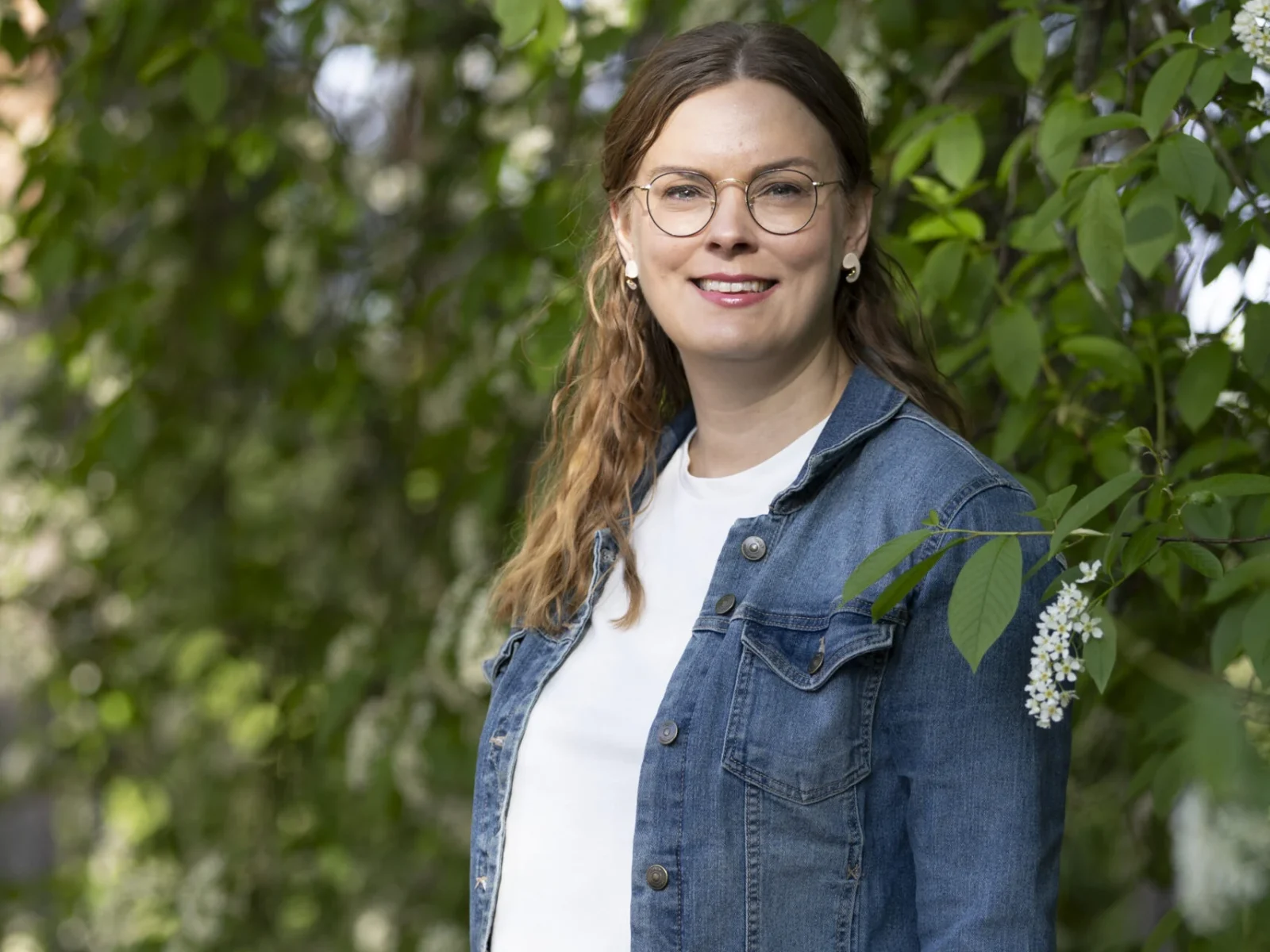 Sari Kokko seisoo kukkivan tuomen alla
